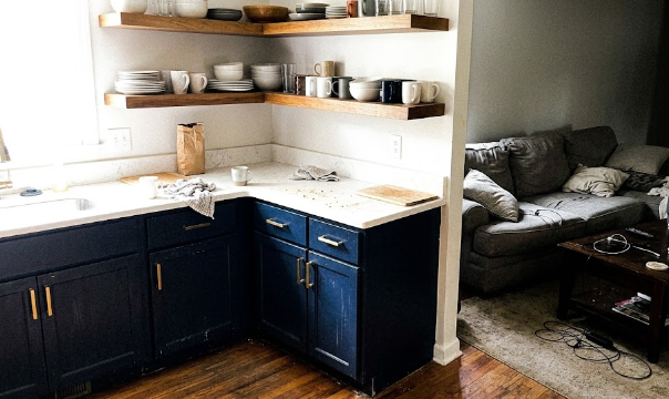 Open concept kitchen renovation with navy blue cabinets, floating shelves, and gold hardware.