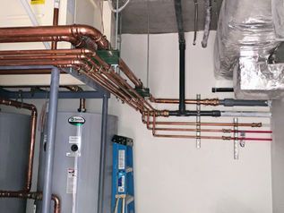 Utility room with copper pipes, water heater, and exposed plumbing along the wall