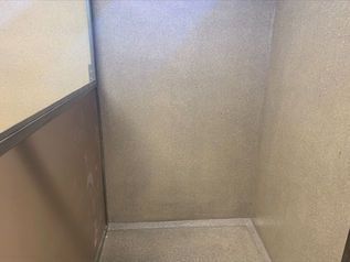 Empty beige stairwell corner with brown trim and gray floor trim