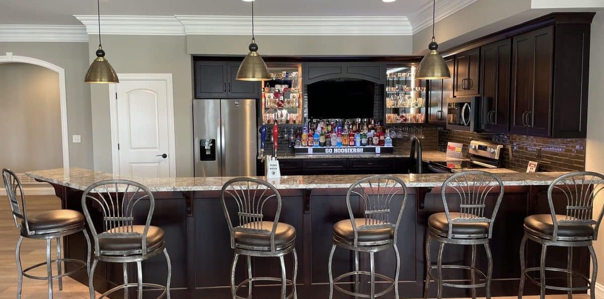Modern kitchen with a long island, bar stools, pendant lights, and dark wood cabinets