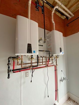 Wall-mounted water heater and boiler with red and black plumbing in a utility room.