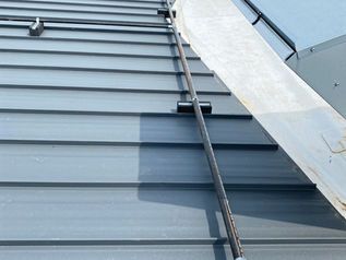 Metal roof with a safety ladder and flashing along the side of a building
