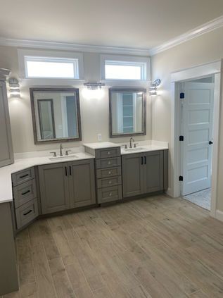 Modern bathroom vanity with dual mirrors, gray cabinets, white counters, and wood-look flooring