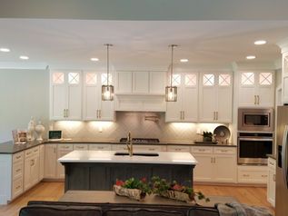 Modern white kitchen with island, pendant lights, and stainless steel appliances