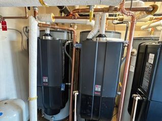 Two black industrial tanks connected by copper pipes in a utility room