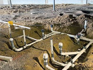 Underground plumbing pipes and valves in a dirt excavation site outdoors