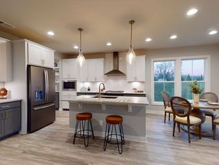 Modern kitchen with white cabinets, island stools, and a dining nook by large windows