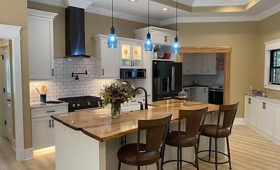Bright modern kitchen with island, pendant lights, bar stools, and flowers on the counter