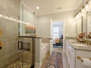 Modern bathroom with glass shower, double vanity, and patterned runner rug