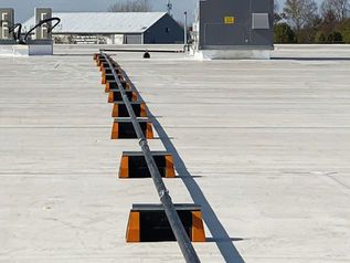 Solar panels mounted in a row across a flat rooftop under a clear sky