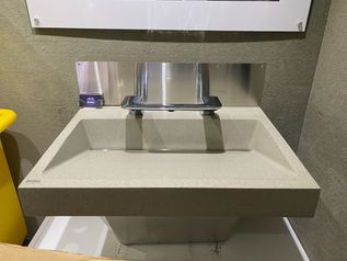 Modern gray wall-mounted sink with a stainless faucet in a restroom