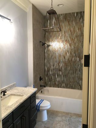 Bathroom with dark vanity, white tub, patterned shower wall, and toilet.