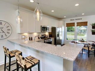 Modern kitchen with large island, pendant lights, stainless appliances, and breakfast nook by a window