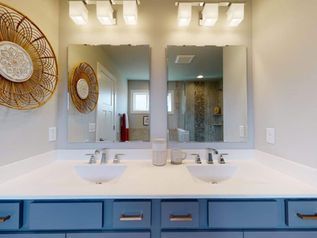 Modern bathroom vanity with double sinks, blue cabinets, large mirrors, and wall sconces
