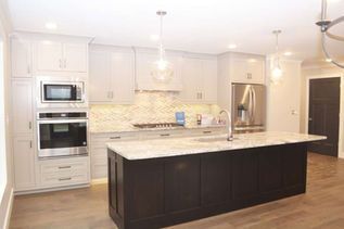 Bright modern kitchen with white cabinets, stainless appliances, and a large dark island counter