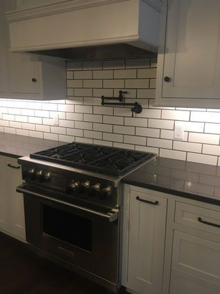Modern kitchen with a stainless steel stove, white subway tile backsplash, and gray cabinets