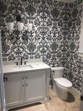 Black-and-white patterned bathroom with vanity, sink, toilet, and three wall lights
