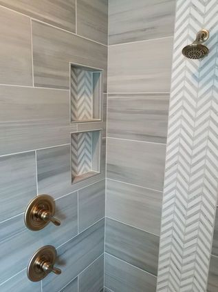 Modern tiled shower with two brass fixtures and recessed wall niches