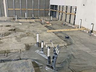 Construction site floor with exposed pipes and plastic sheeting in an unfinished room