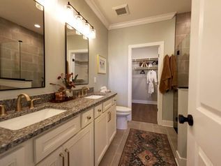 Bathroom with double vanity, granite countertop, large mirror, and a walk-in closet visible through the open door.