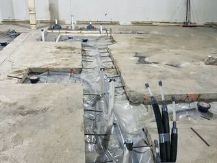 Concrete floor with a long trench and exposed cables in an unfinished room