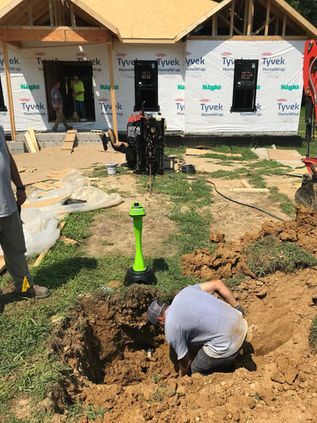 Worker digging a trench at a construction site beside a house under renovation