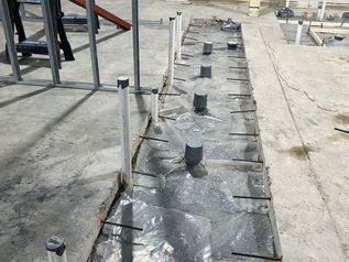 Construction rooftop with black waterproof membrane, vents, and metal framing support posts