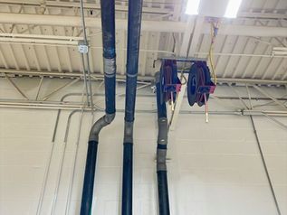Industrial ceiling with blue and black pipes and a red hose reel in a warehouse