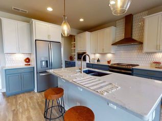 Bright modern kitchen with white cabinets, stainless steel fridge, large island, and wood bar stools