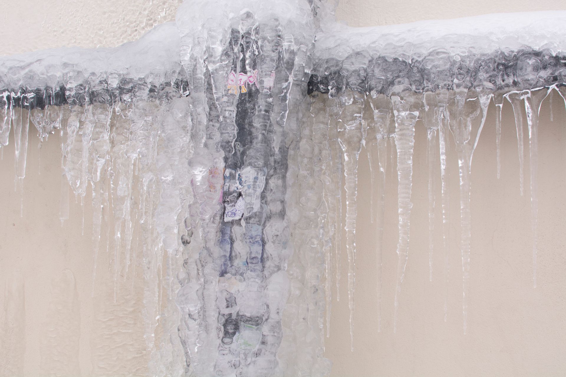 Close-up of an icicle-covered concrete wall with frozen water dripping downward