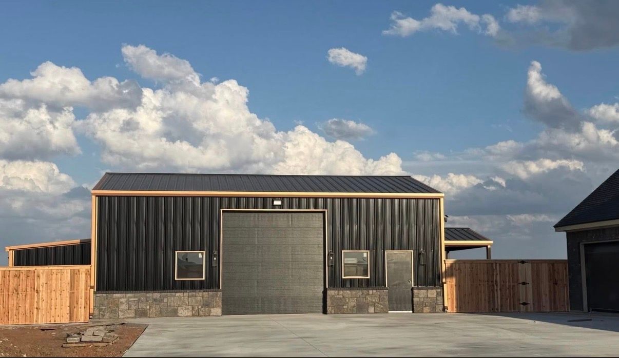 Wooden barn-like building with a large gray garage door under a cloudy blue sky
