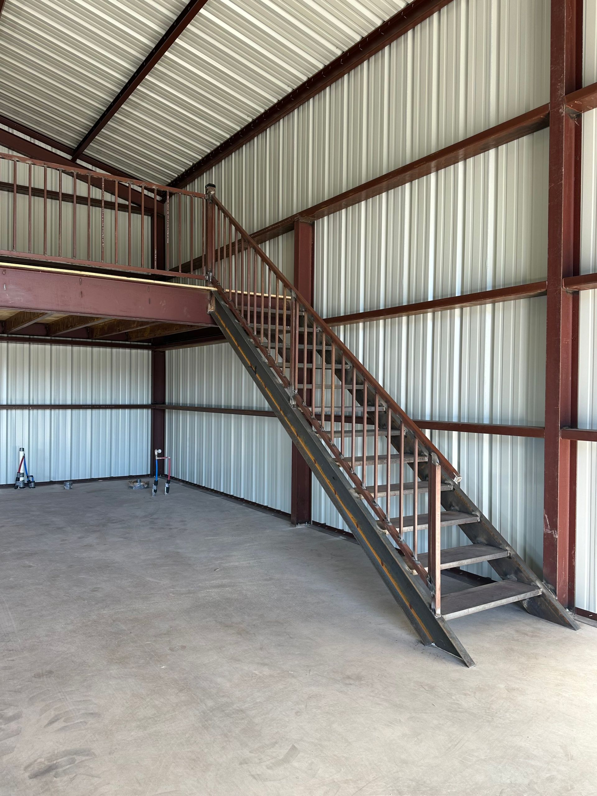 Interior of a metal storage building with a staircase leading to a loft platform