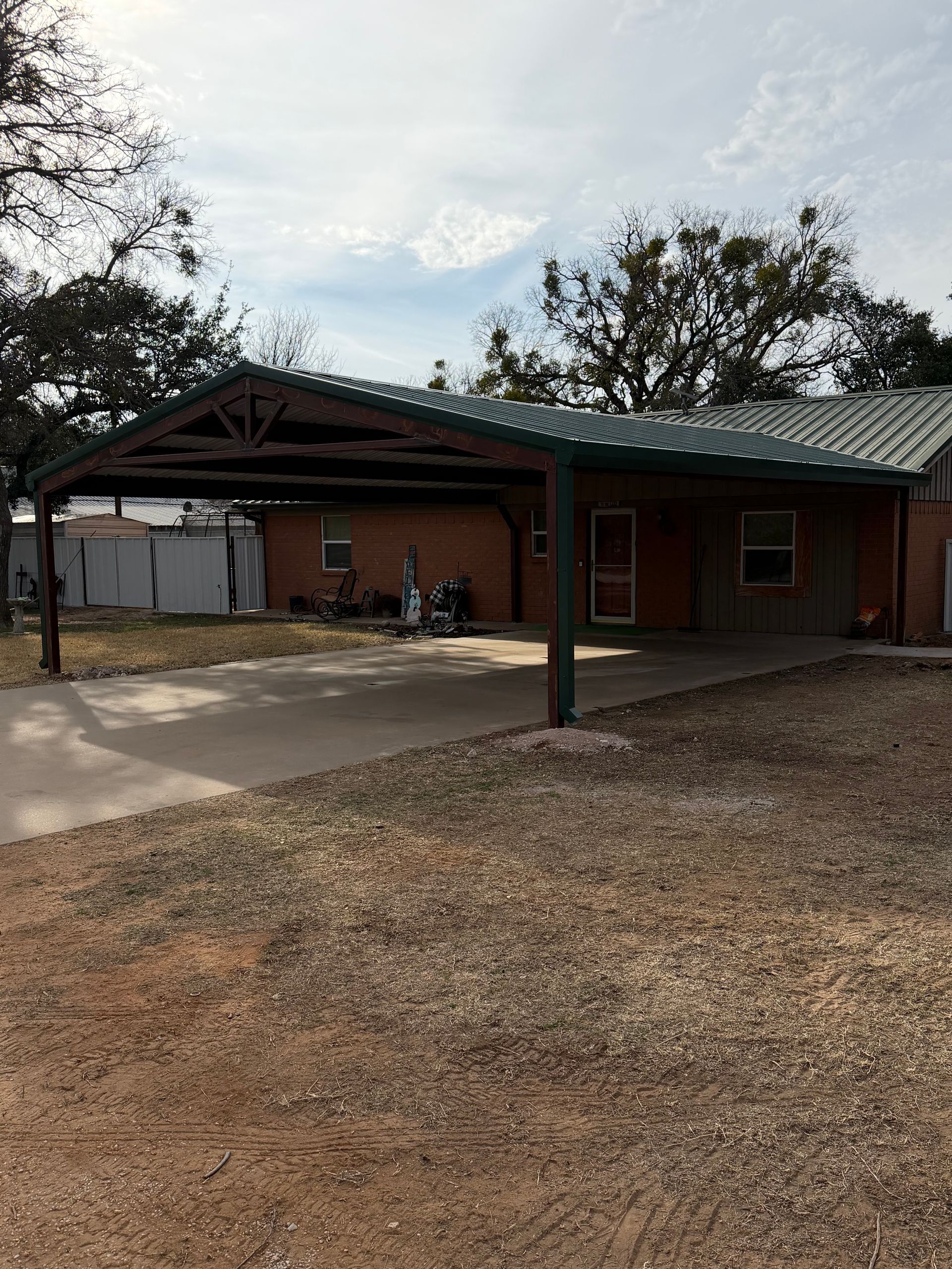 Brick building with green roof and covered entrance, set beside a concrete walkway and gravel yard.