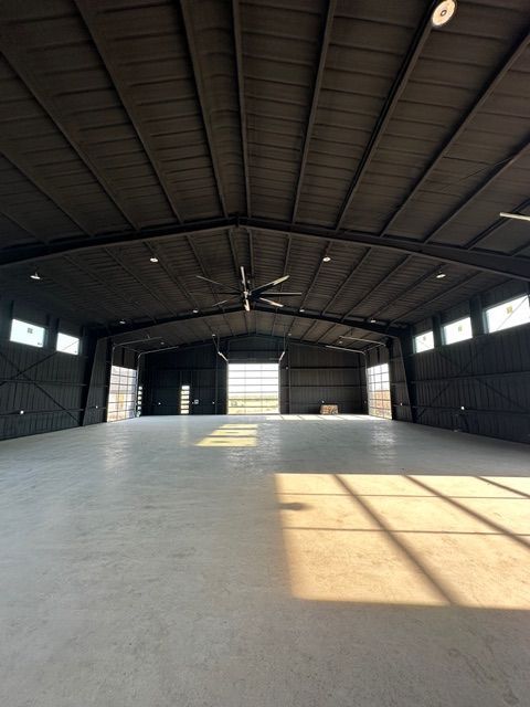 Empty warehouse interior with a concrete floor and sunlight streaming through windows.