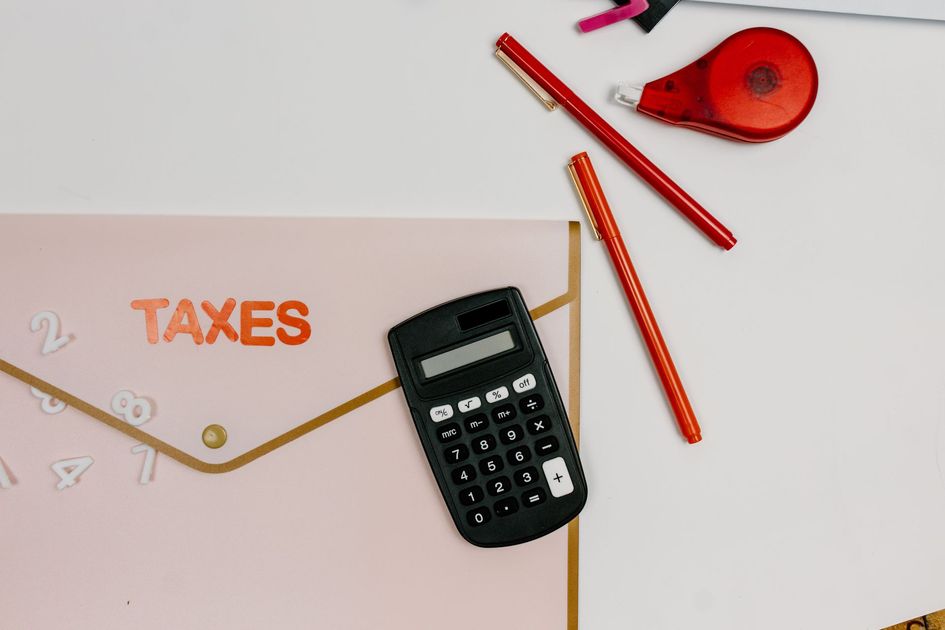 Tax form with calculator, pens, and red tape dispenser on a white desk