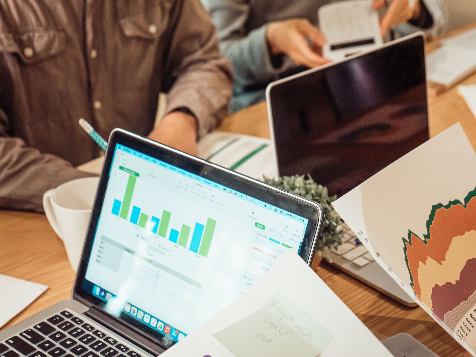 Laptop with colorful bar and line charts on a table in a meeting room