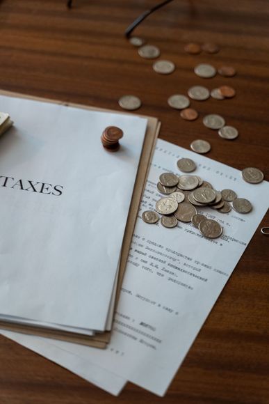 Tax documents with scattered coins on a wooden desk