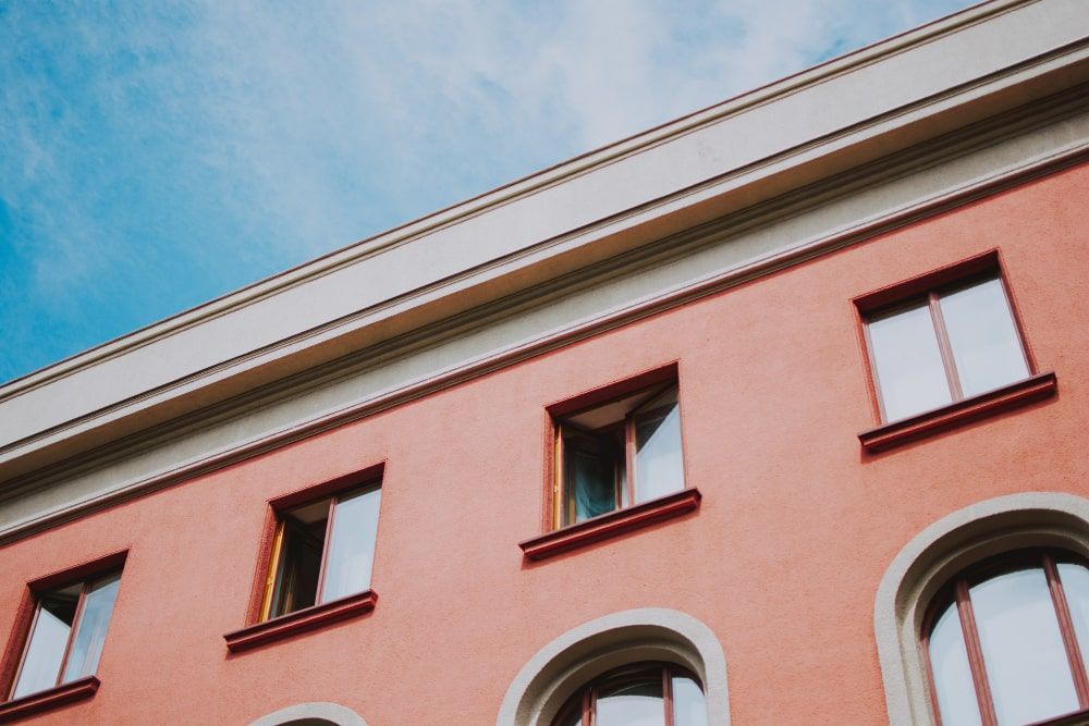 A pink building with arched windows and a blue sky in the background.
