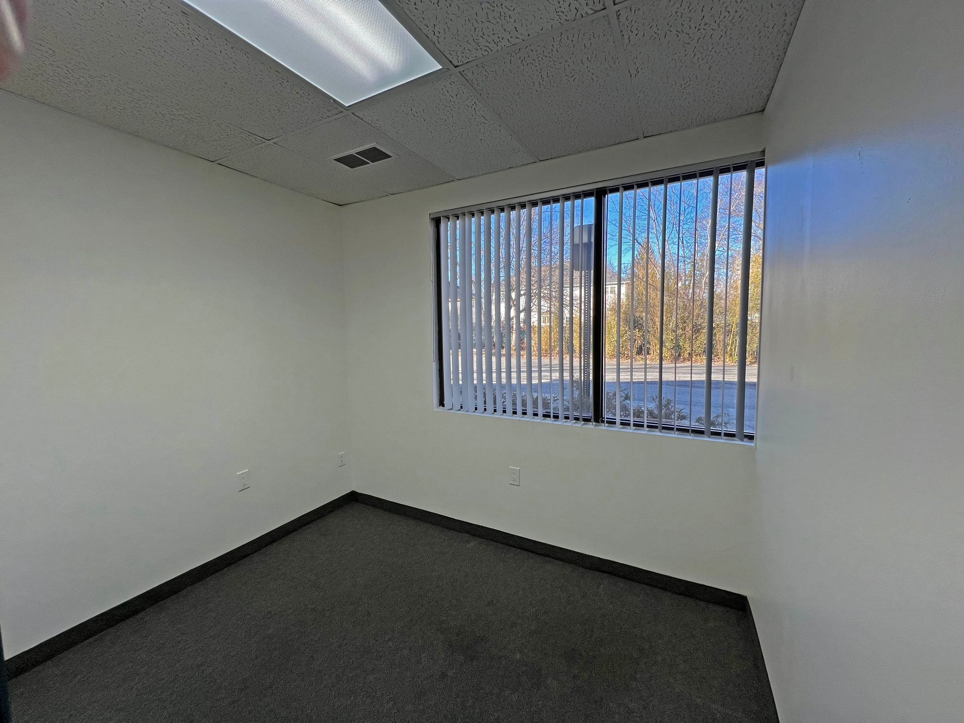 An empty room with a large window and blinds.