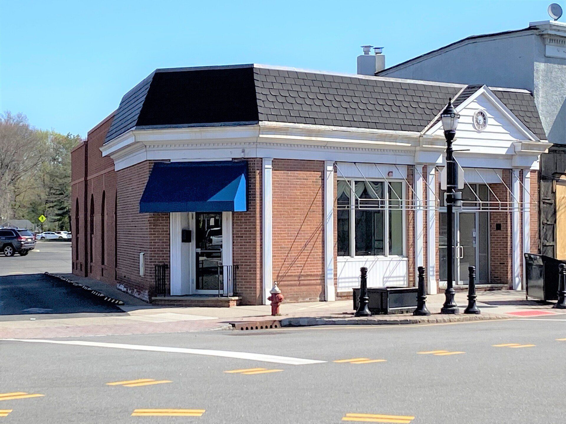 Brick building with blue awning and white trim on a street corner, sunny day.