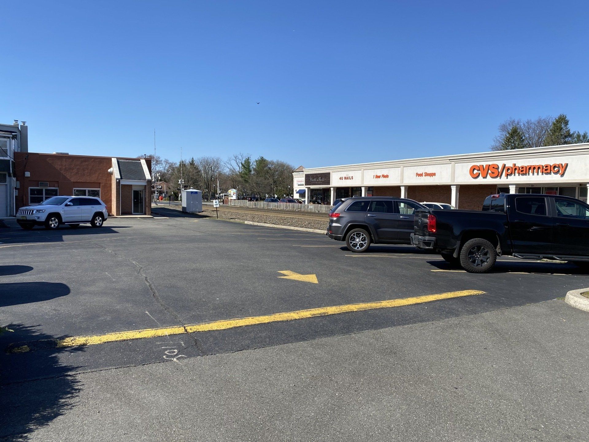 Exterior shot of a parking lot in front of a CVS pharmacy. Cars are parked. Clear, sunny day.