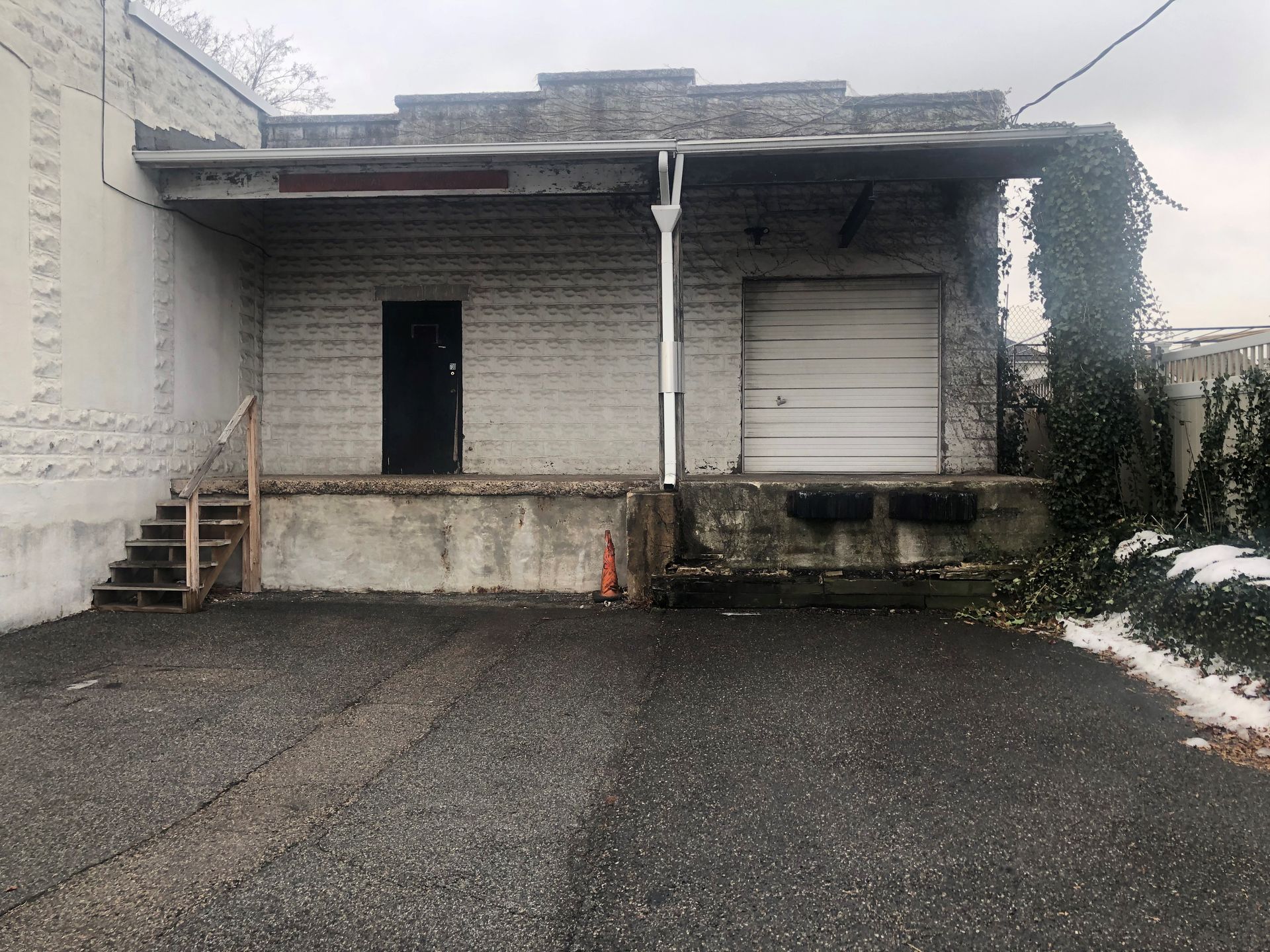 The back of a building with a garage door and stairs.