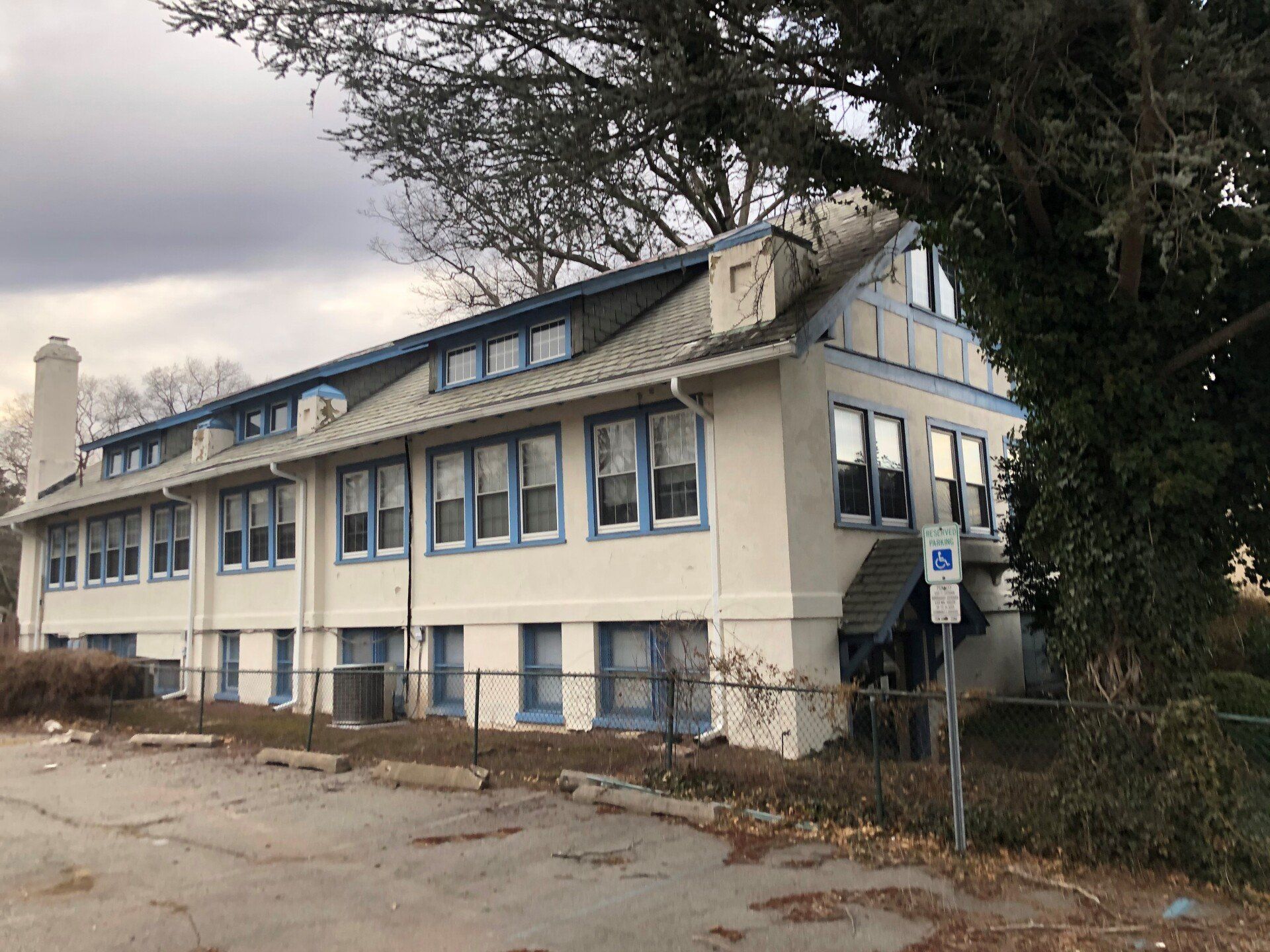 Two-story building with blue trim, a handicap parking sign, and a partially cloudy sky.
