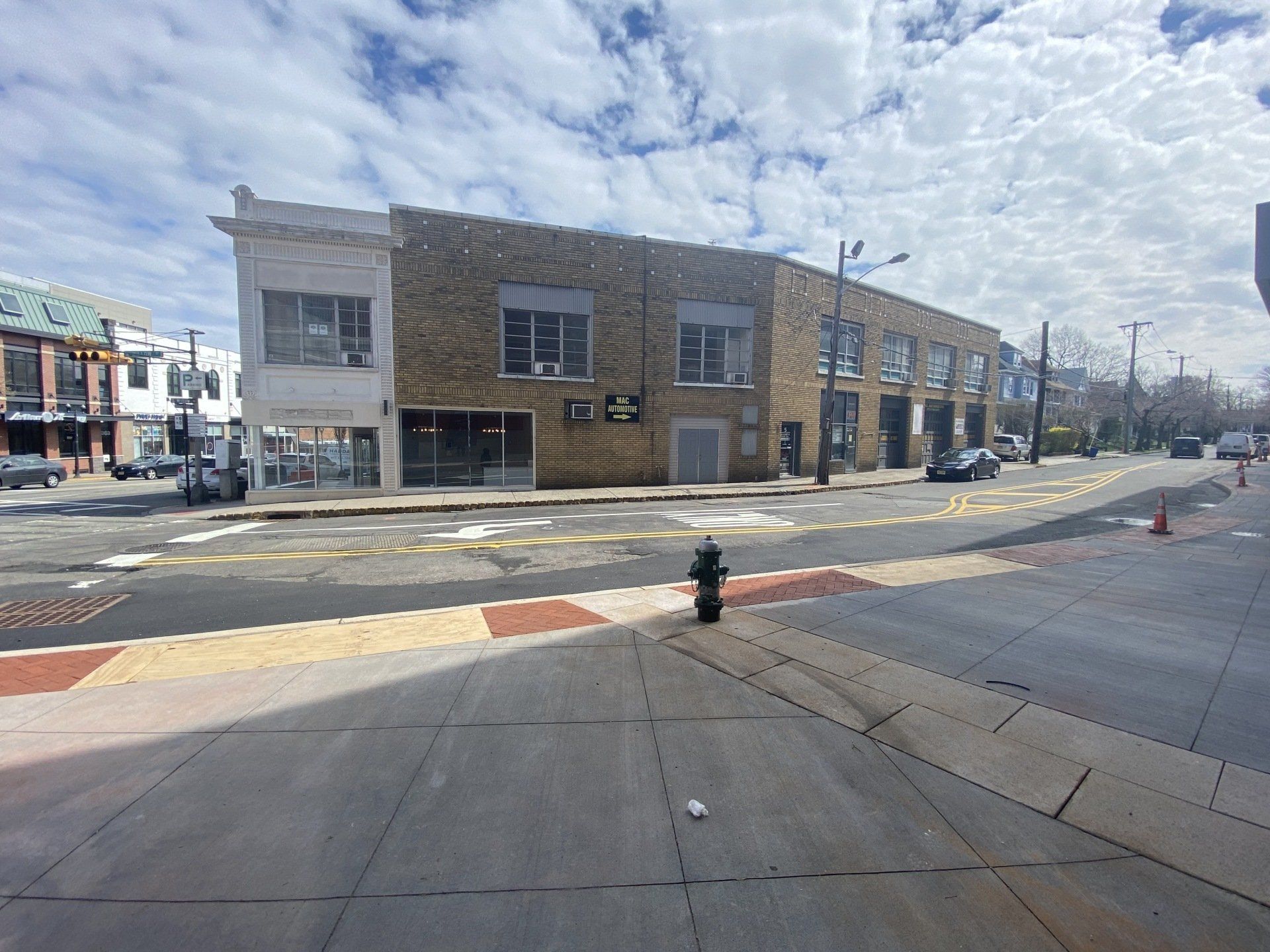 Two-story brick building on a street corner, clear sky above. Sidewalk in the foreground.