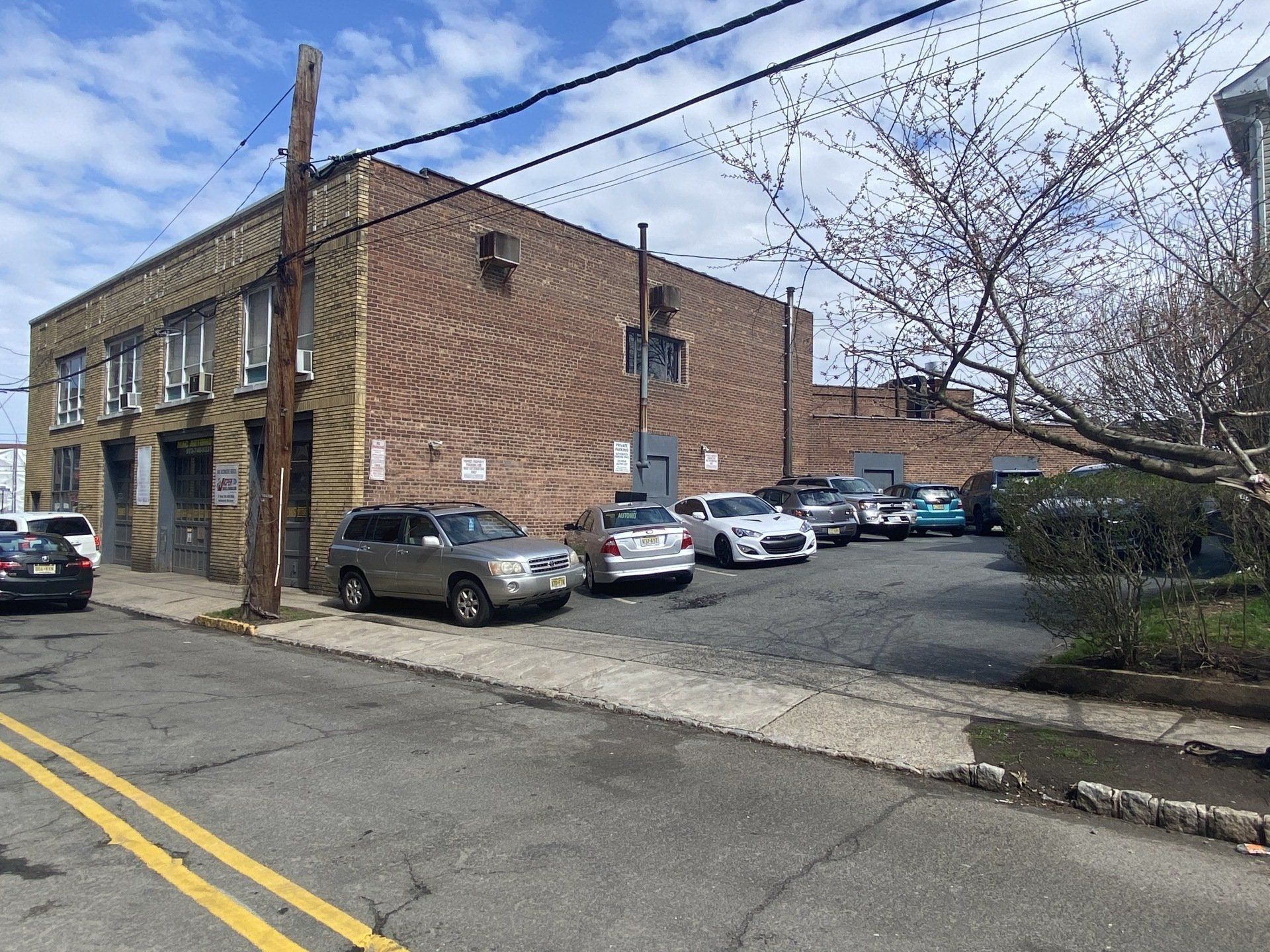 Brick building with parked cars in front; cloudy sky.