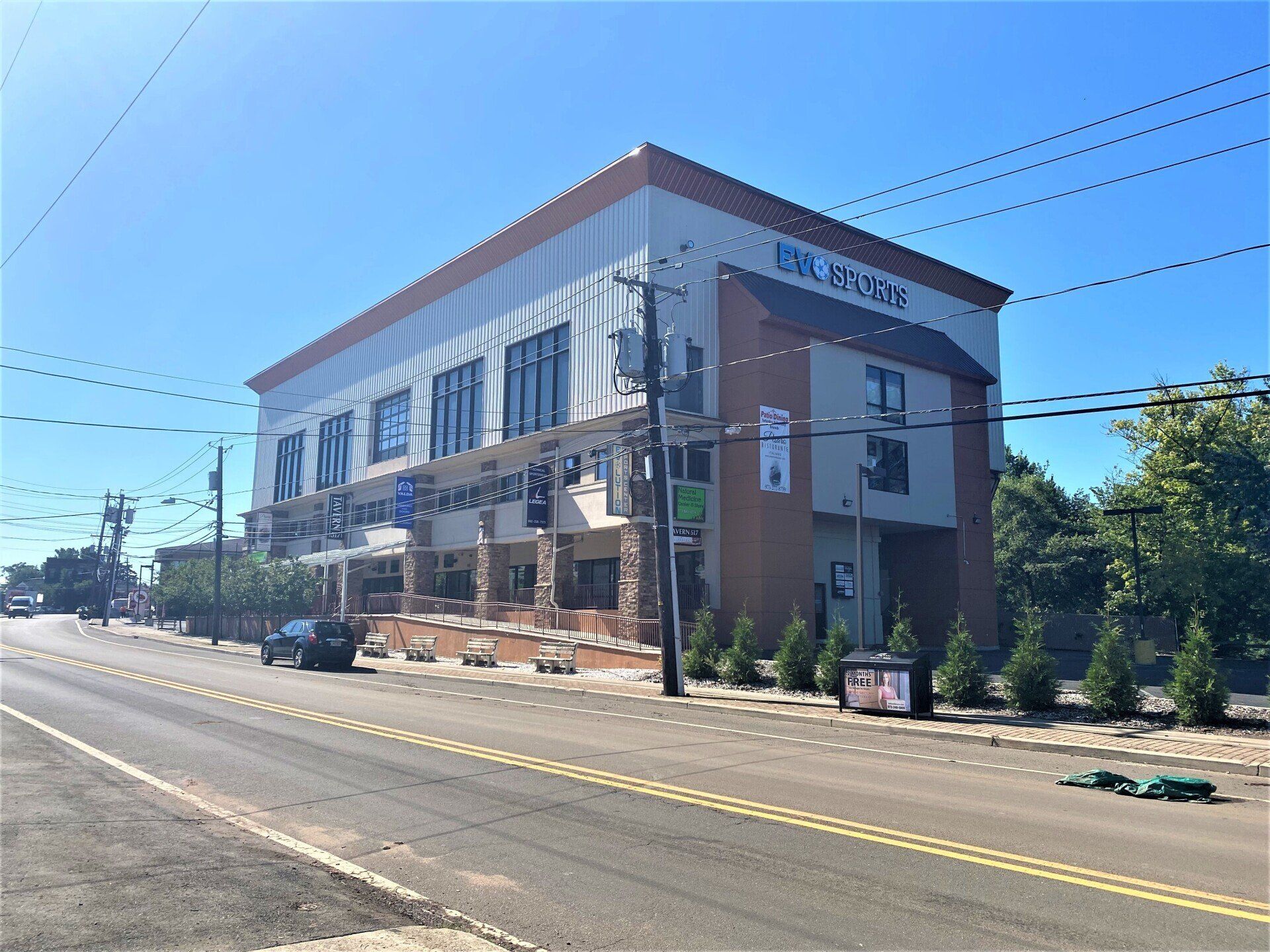 Multi-story building with businesses on a street on a sunny day.