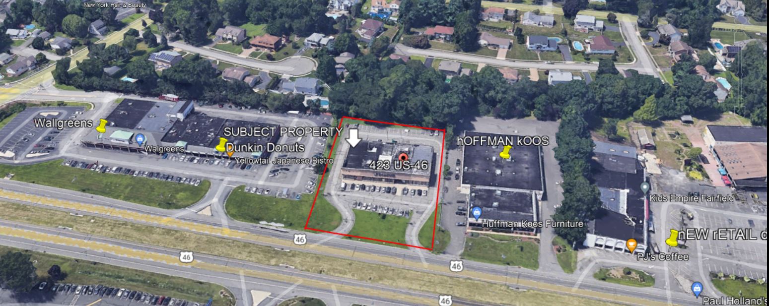 Aerial view of a commercial area with buildings, parking, and a highway.