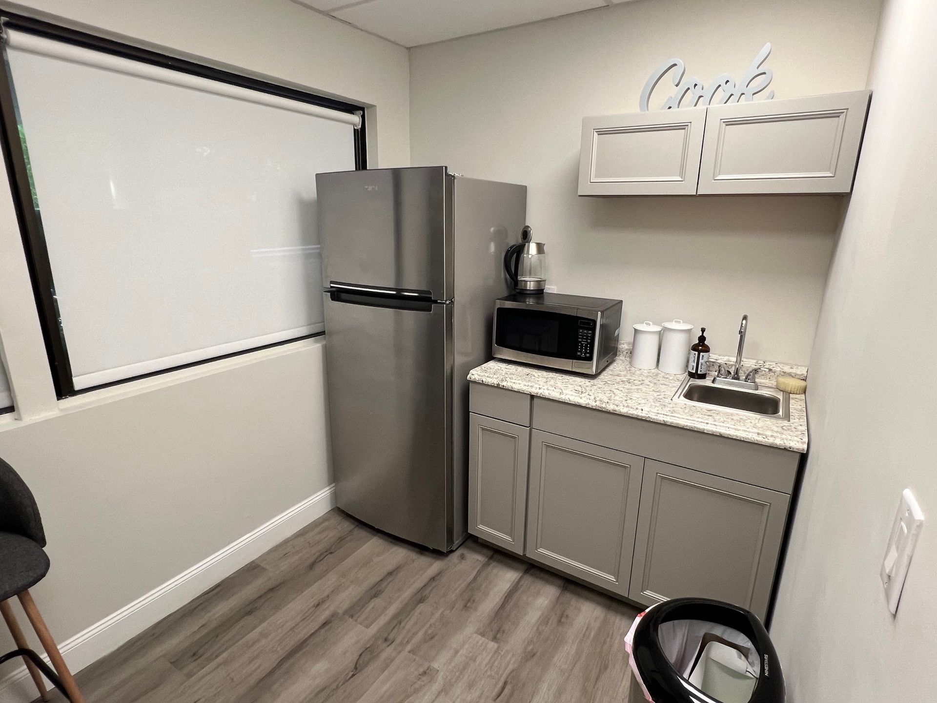 A kitchen with a refrigerator , microwave , sink and cabinets.