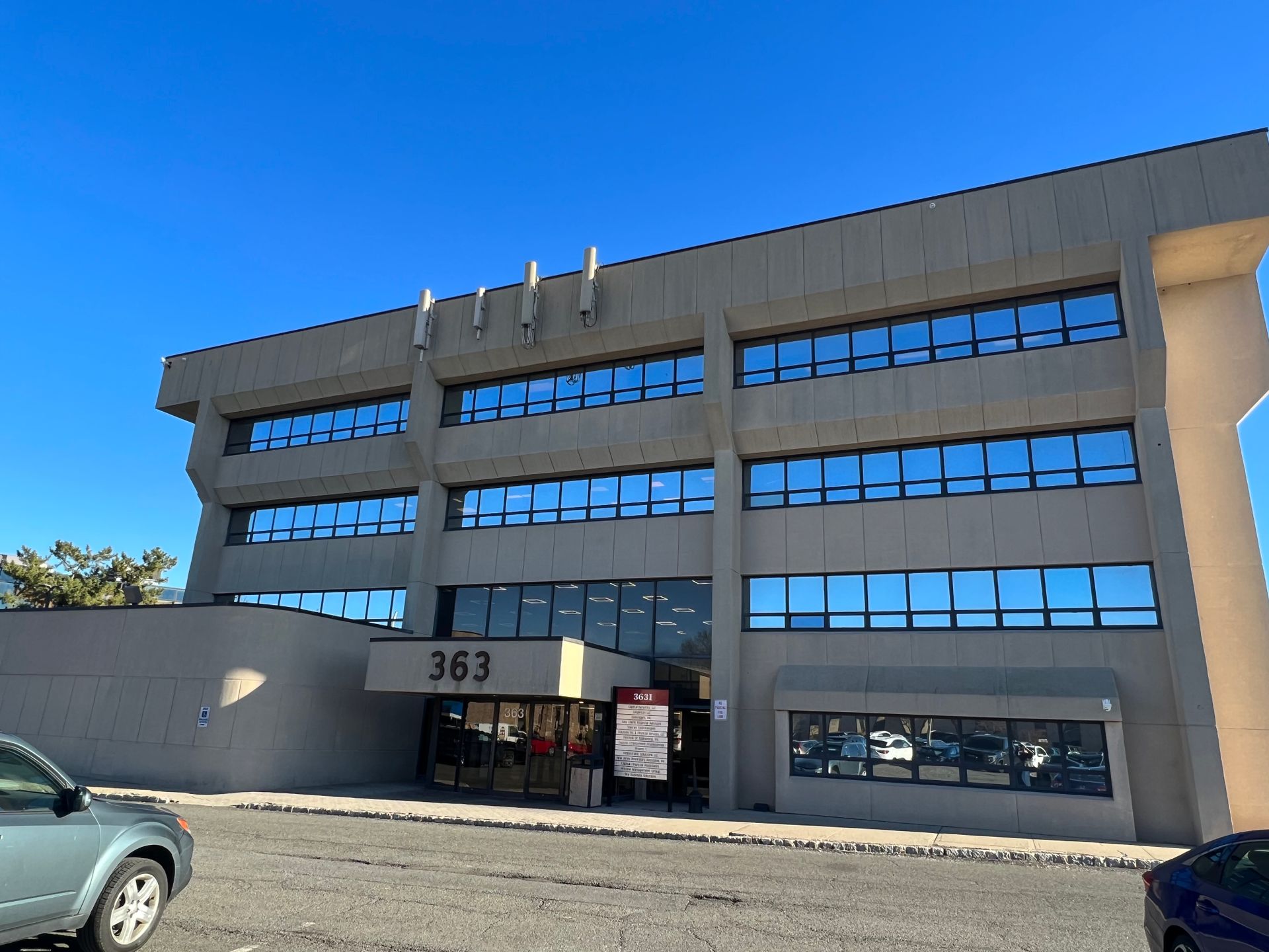Three-story office building with a concrete exterior and numerous windows. The address 
