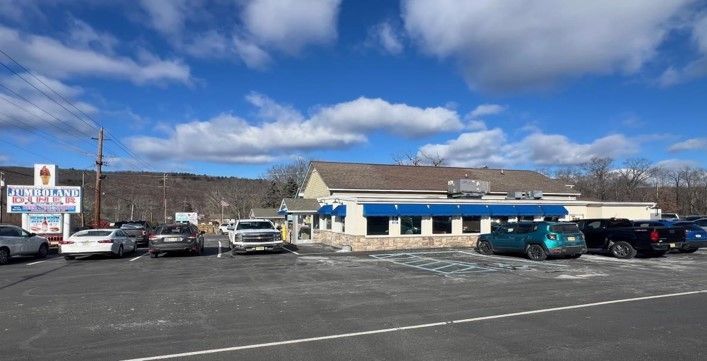 A restaurant with cars parked in front of it on a sunny day.